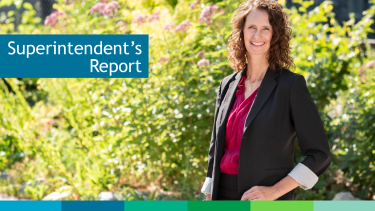 Superintendent Trish Smillie Woman with brown hair standing in front of green bush on a sunny day.